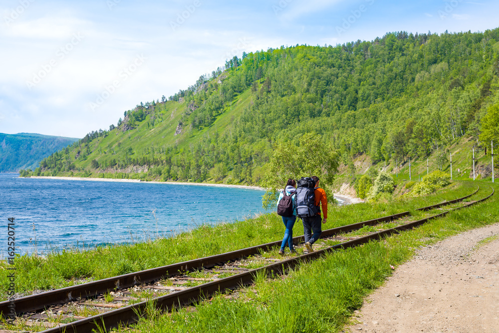 A pair of backpackers go along the Circum-Baikal railway. Lake Baikal, Siberia, Russia