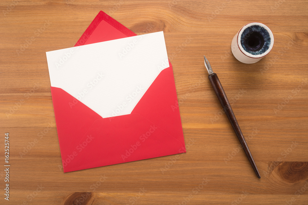 Red envelope, ink pen, inkwell on a wood table Red envelope, ink pen, inkwell on a wood table
