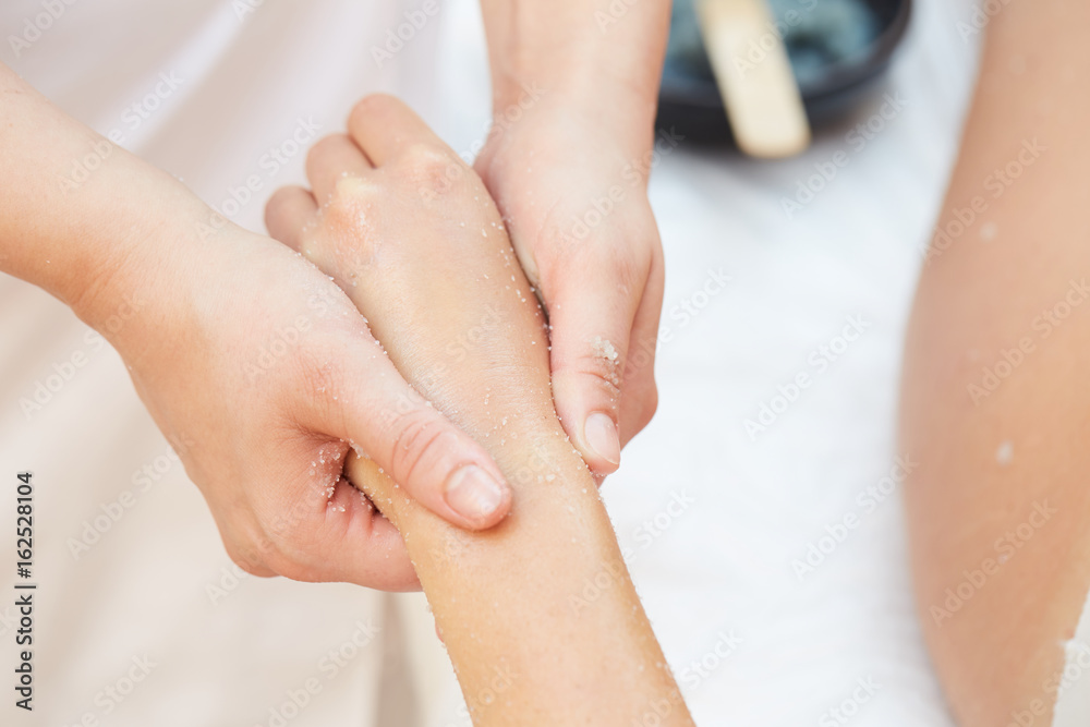 Woman Getting a Salt Scrub Beauty Treatment on hands in the Health Spa