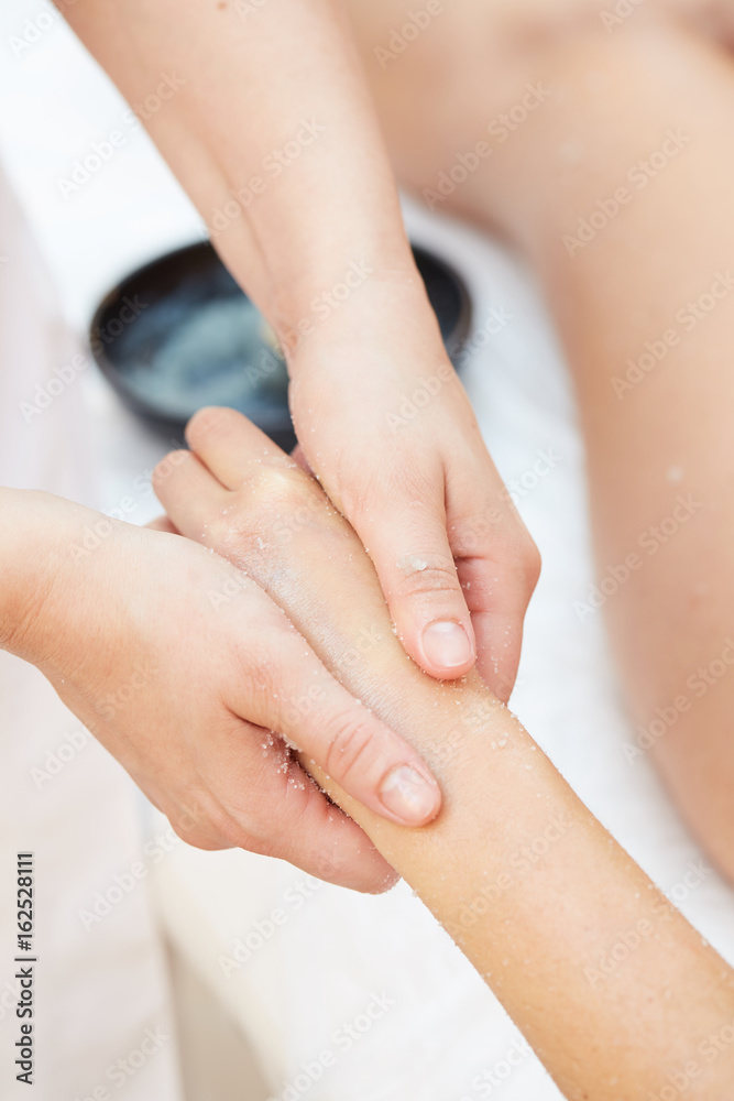 Woman Getting a Salt Scrub Beauty Treatment on hands in the Health Spa Woman Getting a Salt Scrub Beauty Treatment on hands in the Health Spa