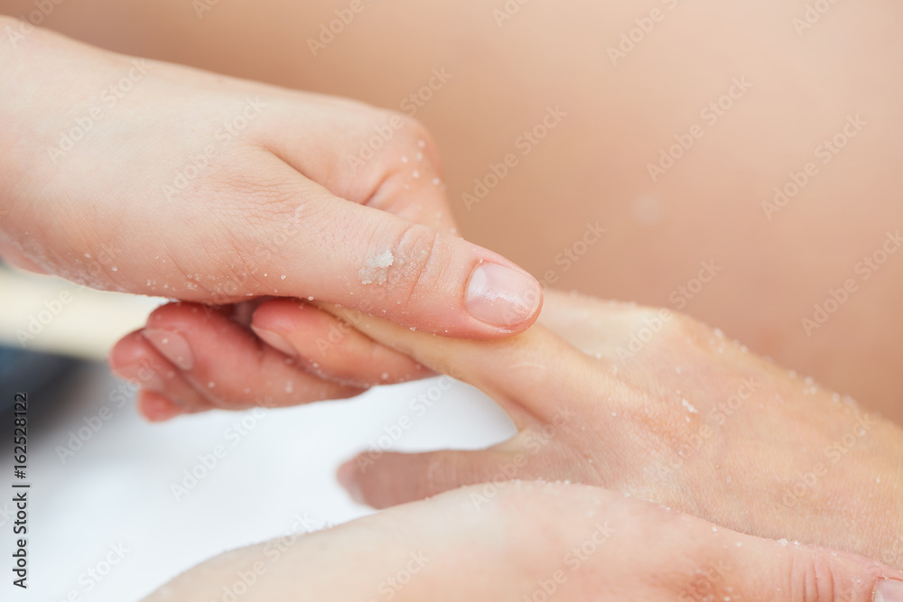 Woman Getting a Salt Scrub Beauty Treatment on hands in the Health Spa Woman Getting a Salt Scrub Beauty Treatment on hands in the Health Spa