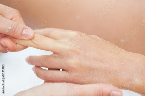 Woman Getting a Salt Scrub Beauty Treatment on hands in the Health Spa
