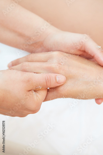 Woman Getting a Salt Scrub Beauty Treatment on hands in the Health Spa