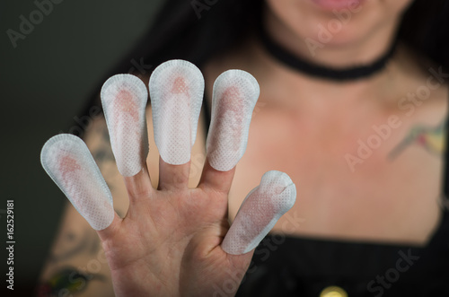 Close up of young woman wearing nails protector in her nails, hand and ideal clean manicure, in a black background photo