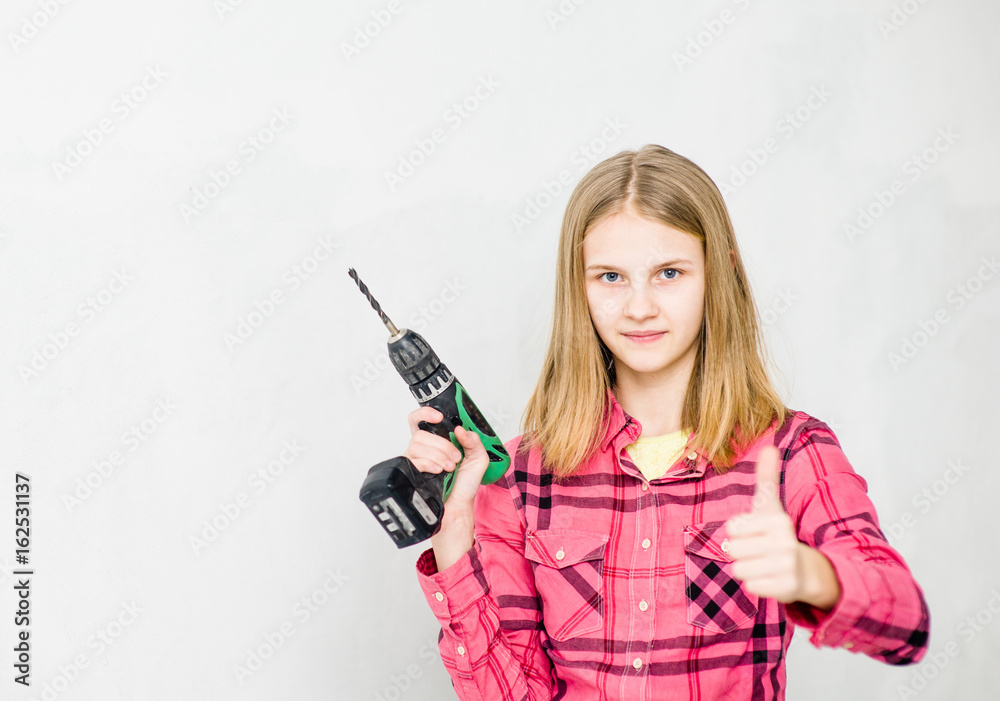 Happy teen girl with drill showing thumbs up Happy teen girl with drill showing thumbs up