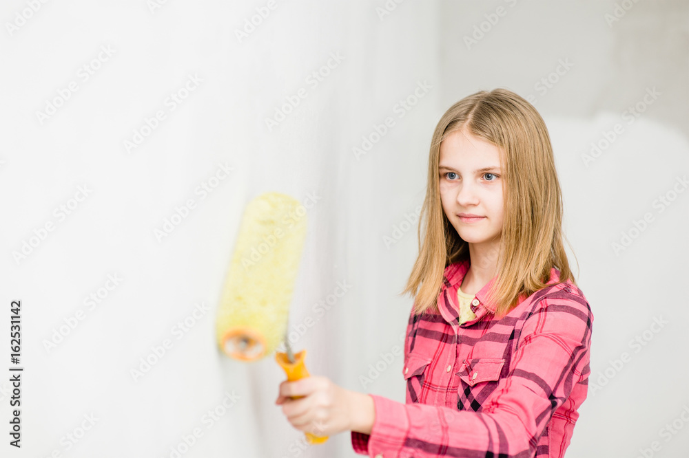 Teen girl painting the wall with paint roller Teen girl painting the wall with paint roller