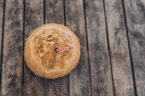 tropical landscape. fresh coconut with a straw on a sandy beach