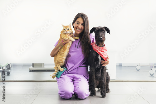Cheerful women veterinary holding a yellow cat and dog. photo