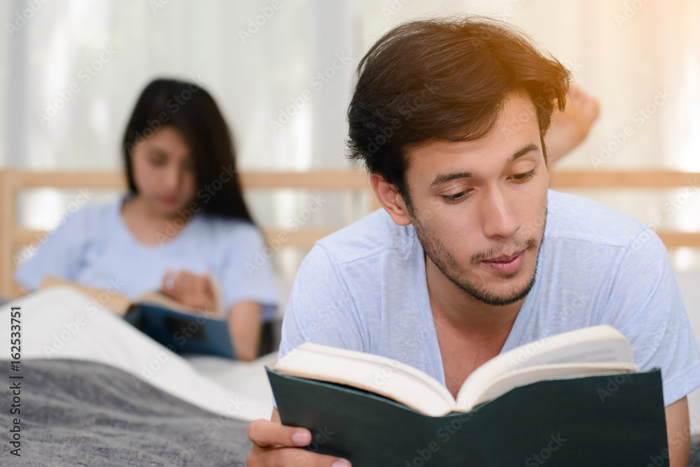Couple reading a book together in bedroom, focused on male. Couple reading a book together in bedroom, focused on male.