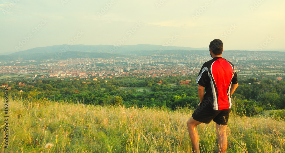 Hiker looking city panorama in the evening from the mountains above. Looking at city of Nis, serbia from the hill Vinik Hiker looking city panorama in the evening from the mountains above. Looking at city of Nis, serbia from the hill Vinik