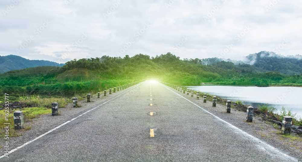 Goals or Finishes Line Concept. Perspective View of Asphalt Road Between Forests and Rivers to Mountain with Trees and Cloudy Sky in Summer Season, Thailand as Copyspace to mock up or input text