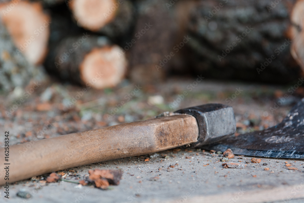 Axe and firewood. The axe lies near firewood. Axe and firewood. The axe lies near firewood.