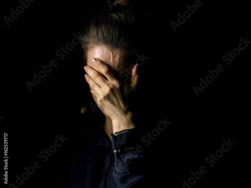 Fotografie stressed woman in dark dress isolated on black background