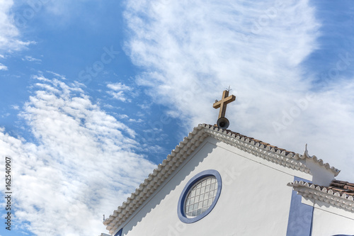 white church with a cross and blue sky full of clouds photo