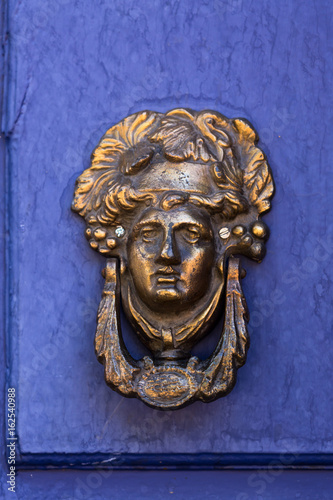 antique door handle on a blue dor, woman face
