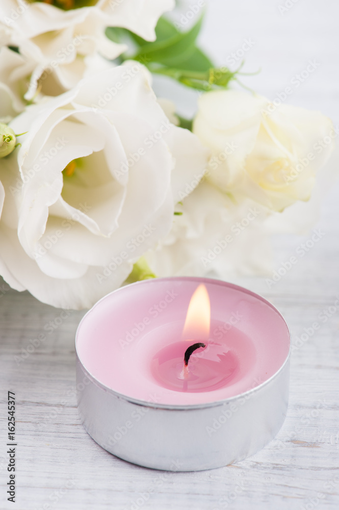 Arrangement of white eustoma flowers and pink lit candle