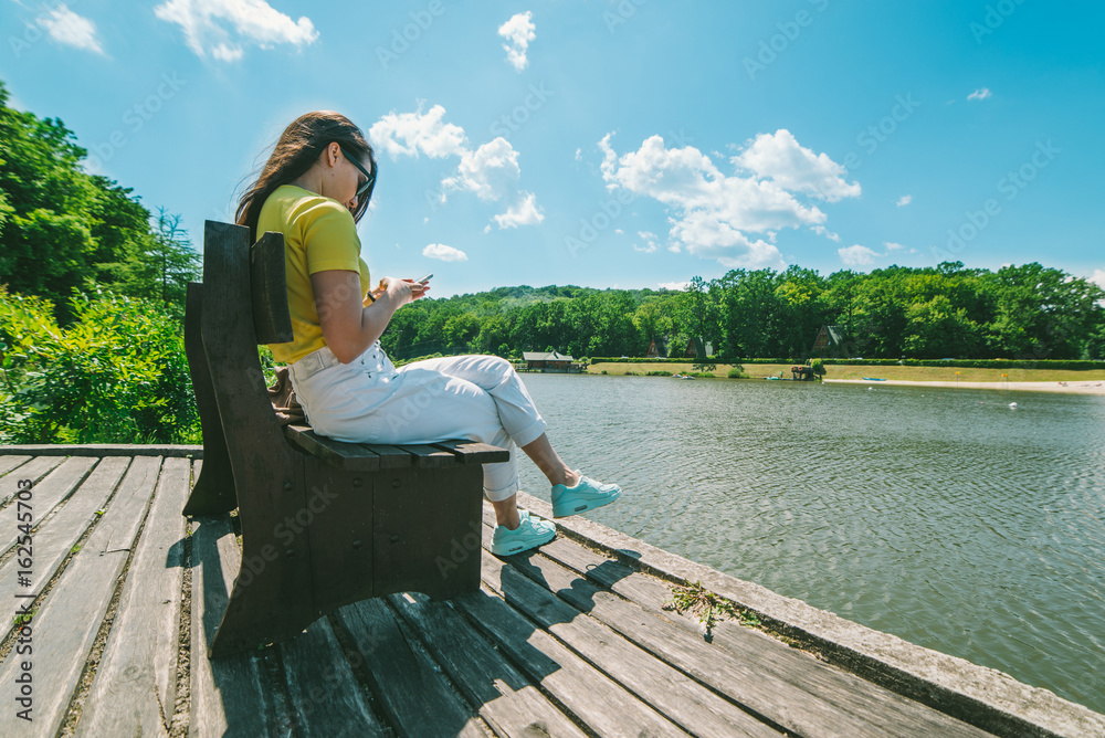 Fototapeta premium young pretty woman sitis on the bench