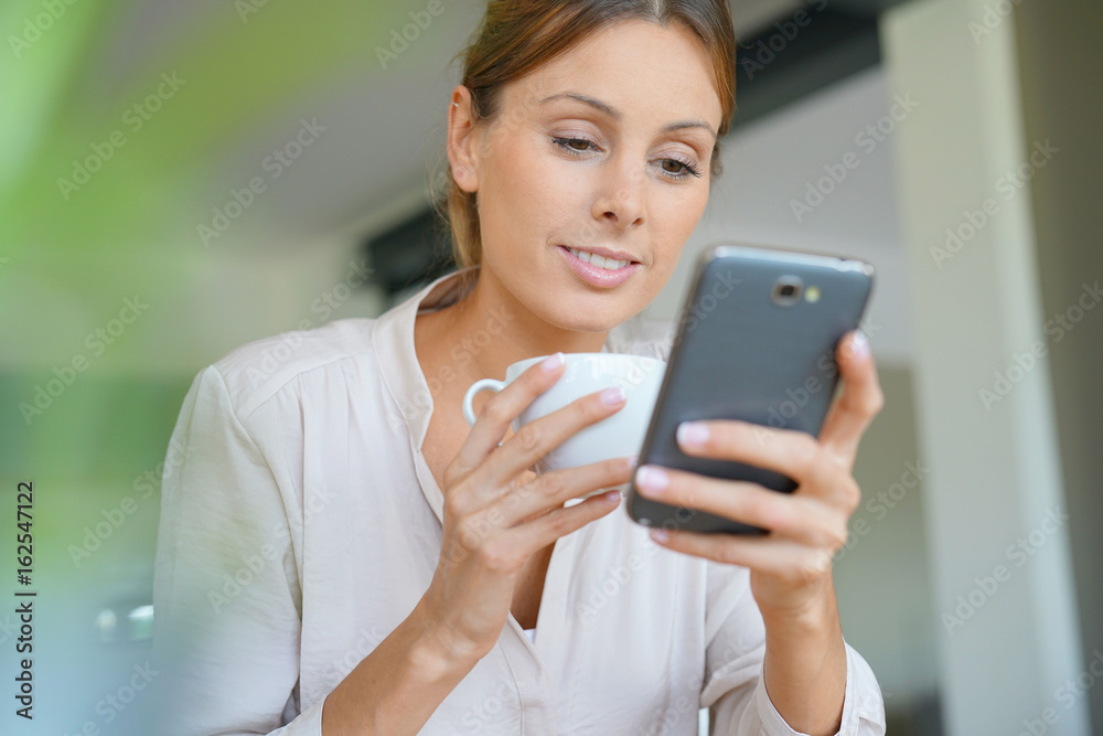 Woman with cup of coffee using smartphone Woman with cup of coffee using smartphone