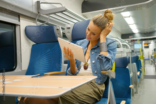 Smiling young woman in train connected on tablet