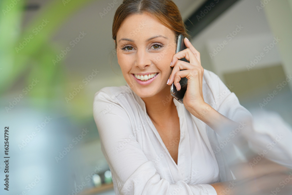 Woman sitting at desk talking on mobile phone Woman sitting at desk talking on mobile phone