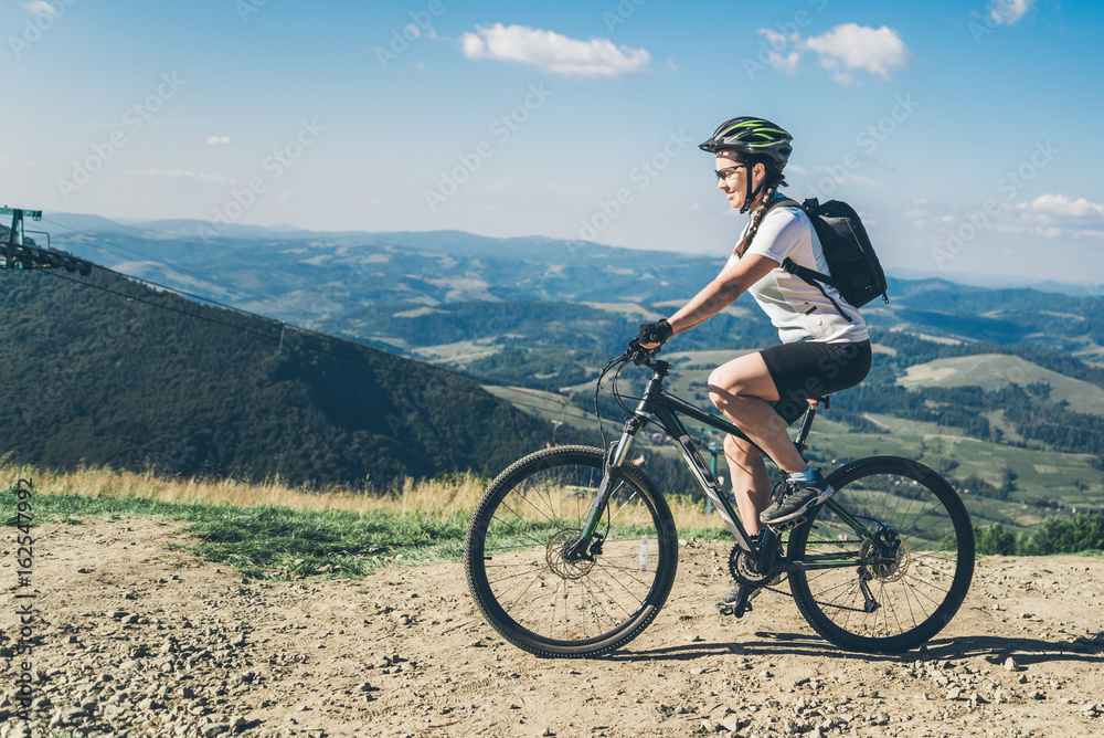 Fototapeta premium Young woman riding on MTB in mountains