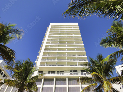 White modern apartment building with palm trees and blue sky. © Nancy Pauwels