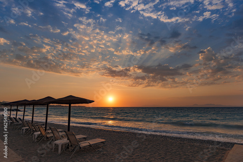 Beautiful sunset contre-jour on the sea shore  in a beach resort  with comfortable sunbeds and umbrellas