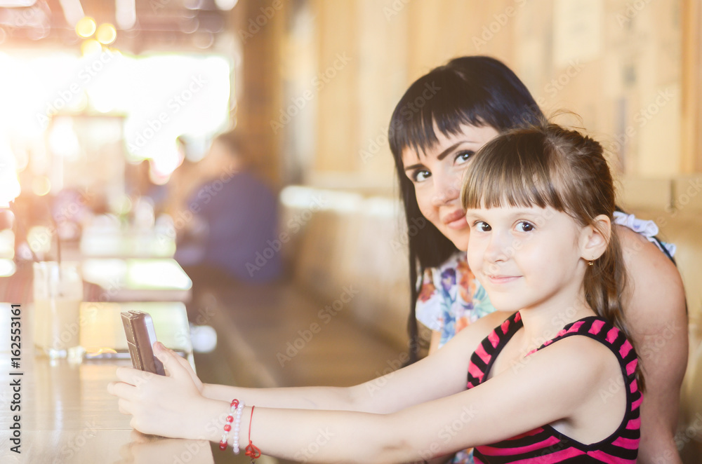 girl with a mom plays a game or uses the applications on the phone girl with a mom plays a game or uses the applications on the phone