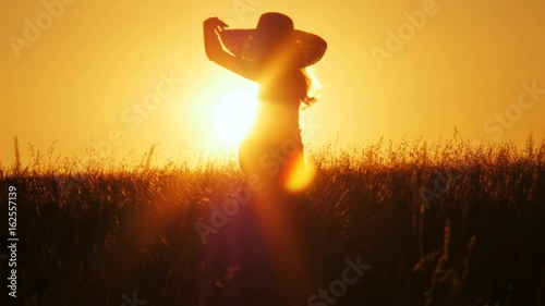 Attractive young woman silhouette dancing outdoors on a sunrise with sun shining bright behind her on a horizon. 4k shot