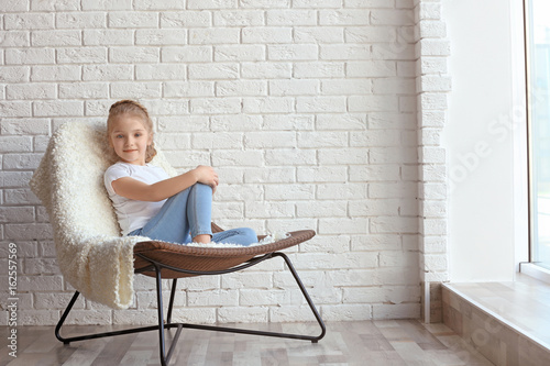 Small girl sitting on chair...