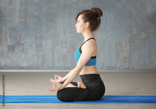 Young woman practicing yoga on floor indoors