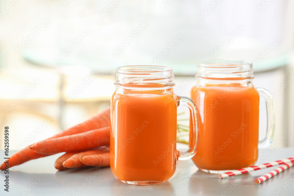 Jars of carrot juice on table Jars of carrot juice on table