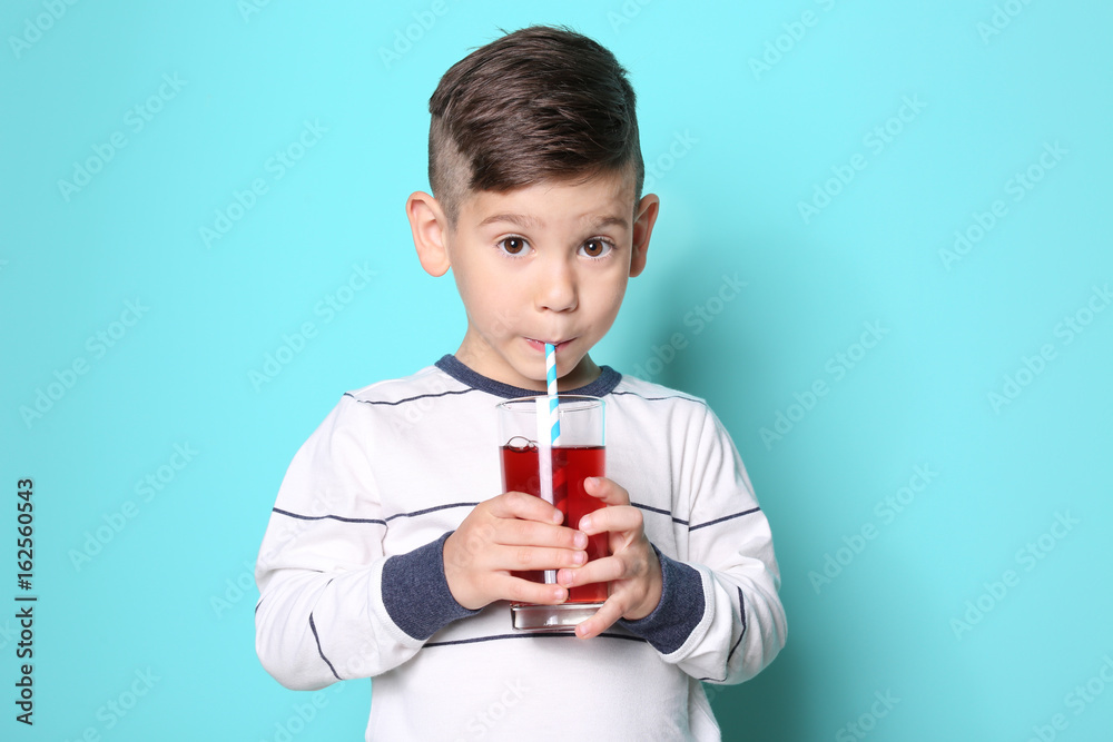 Cute little boy drinking juice on color background Cute little boy drinking juice on color background