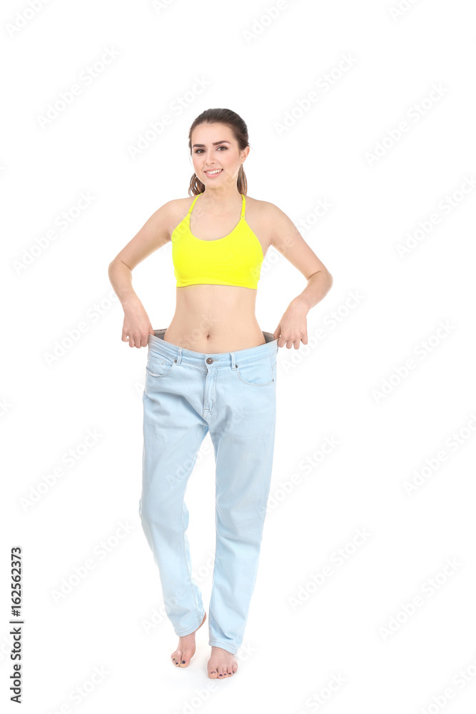 Beautiful young woman in oversized jeans on white background. Diet concept Beautiful young woman in oversized jeans on white background. Diet concept