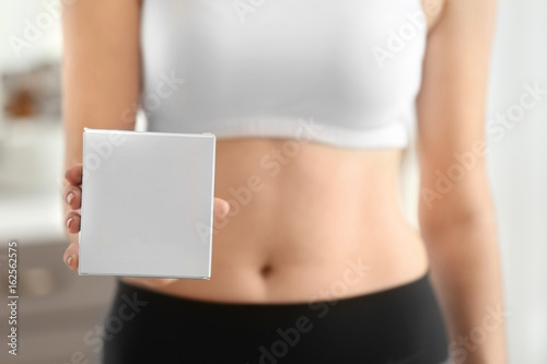 Beautiful young woman with biologically active supplement at home, closeup. Diet concept