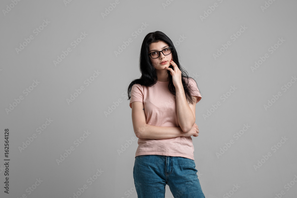 Portrait of smart beautiful brunette girl in eyeglasses with natural make-up, on grey background. Portrait of smart beautiful brunette girl in eyeglasses with natural make-up, on grey background.