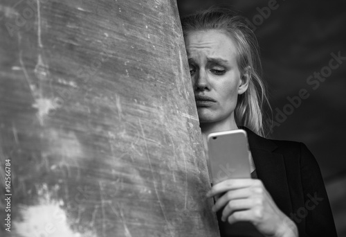 Depressed woman using a mobile phone. Bad news. Sorrow.