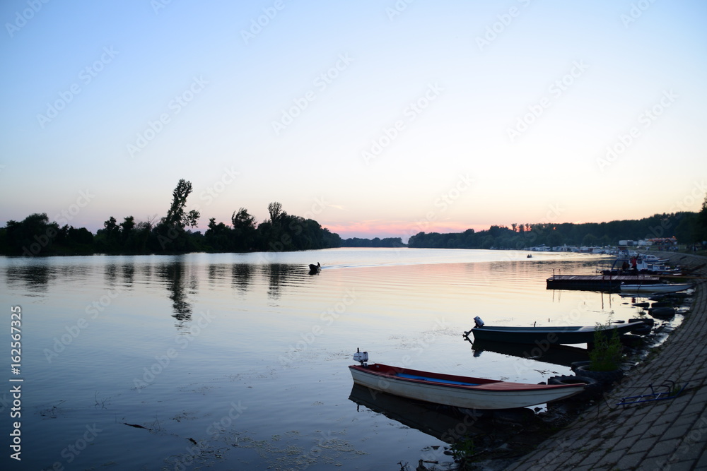 silhouette of a man in a boat that floats in the river at sunset