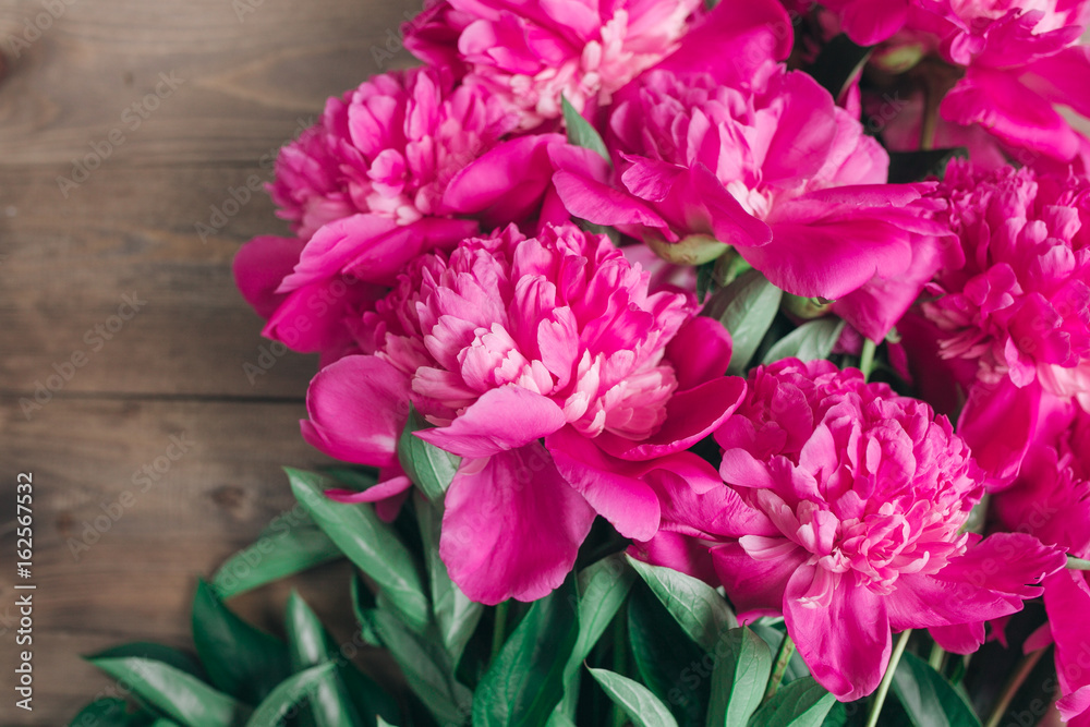 Row of peonies on wooden background with space for message. Women's or Mother's Day background. Top view Row of peonies on wooden background with space for message. Women's or Mother's Day background. Top view