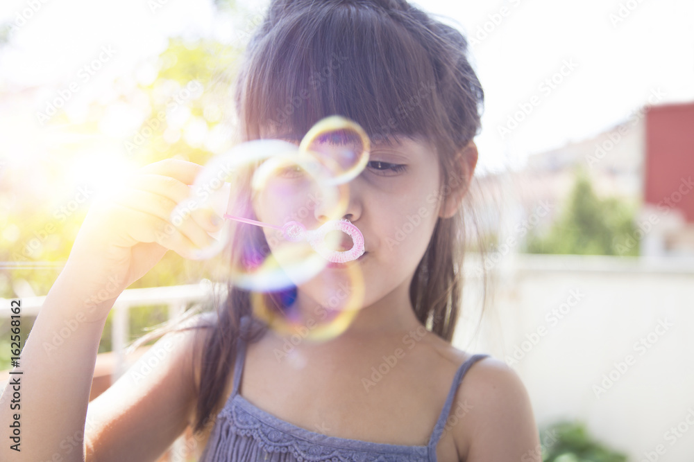Cute little girl is blowing a soap bubbles, outdoor shoot Cute little girl is blowing a soap bubbles, outdoor shoot