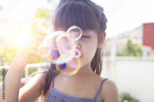 Cute little girl is blowing a soap bubbles, outdoor shoot 