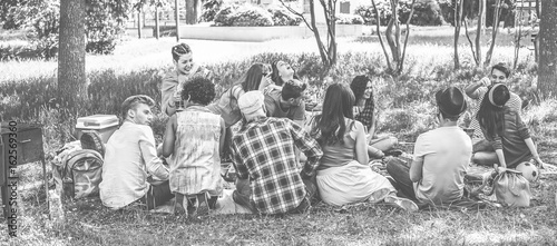 Group of friends making picnic with barbecue on city park outdoor - Young people eating bbq meal and drinking wine - Focus on bottom guys - Black and white editing - Youth concept - Vintage filter