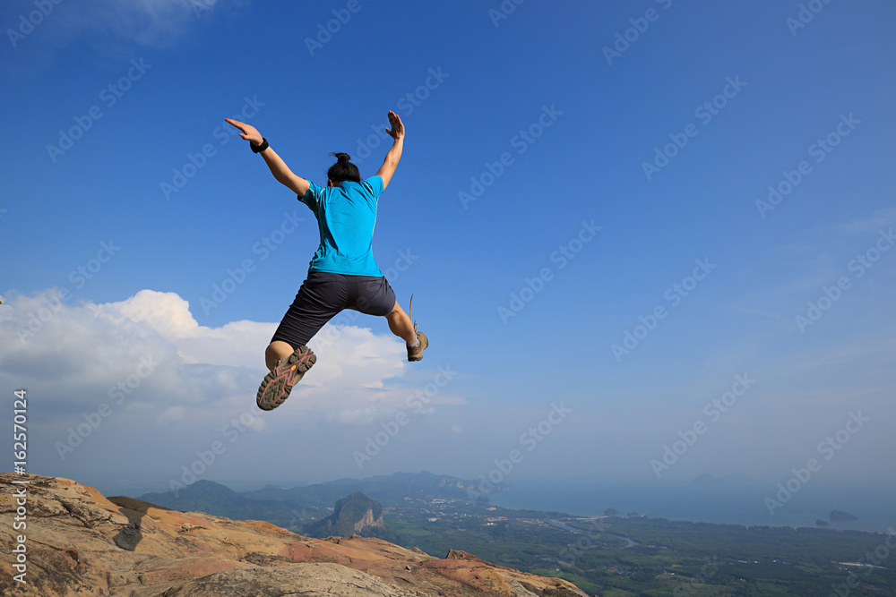 Young woman jumping on mountain peak