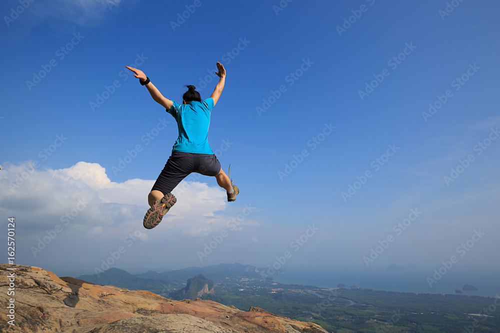 Young woman jumping on mountain peak Young woman jumping on mountain peak