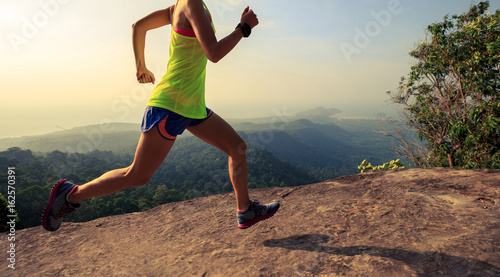 Young woman running on mountain top rock © lzf