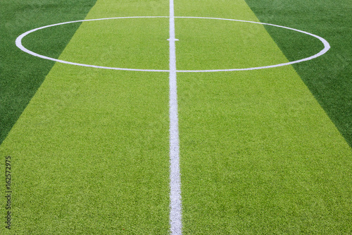 Photo of a green synthetic grass sports field with white line shot from above.