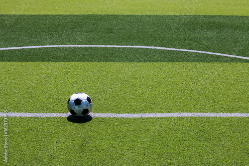The old soccer football on the white line in the artificial turf