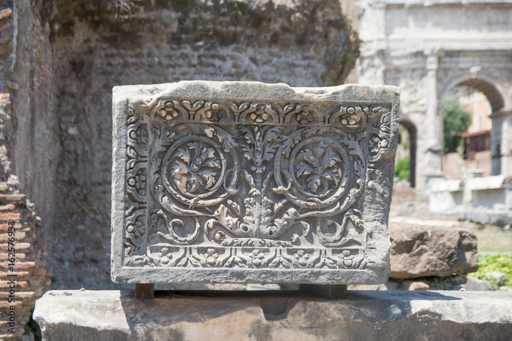 A stone block carved with a floral decoration created by the Roman Empire. The block is located in the Roman Forum in Rome, Italy