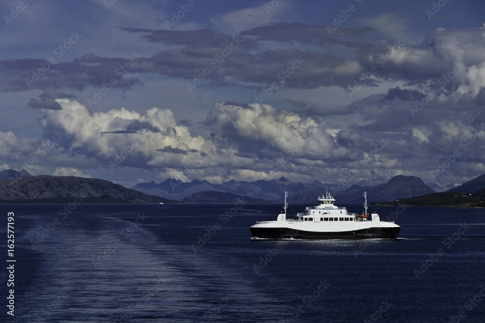  Passing the ferry Heroysund near Bronnysund, Norway, under storm clouds, with mountains in background