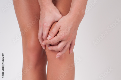 Close-up of female hands touching leg  feeling pain in knee.
